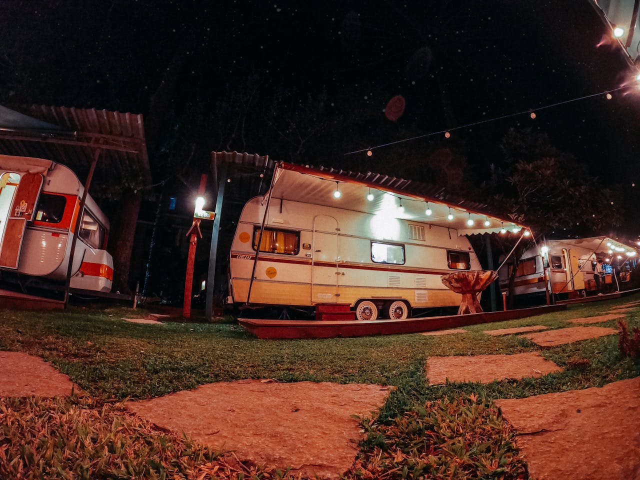 Cozy, illuminated caravans in a nighttime park setting, perfect for travel and adventure enthusiasts.